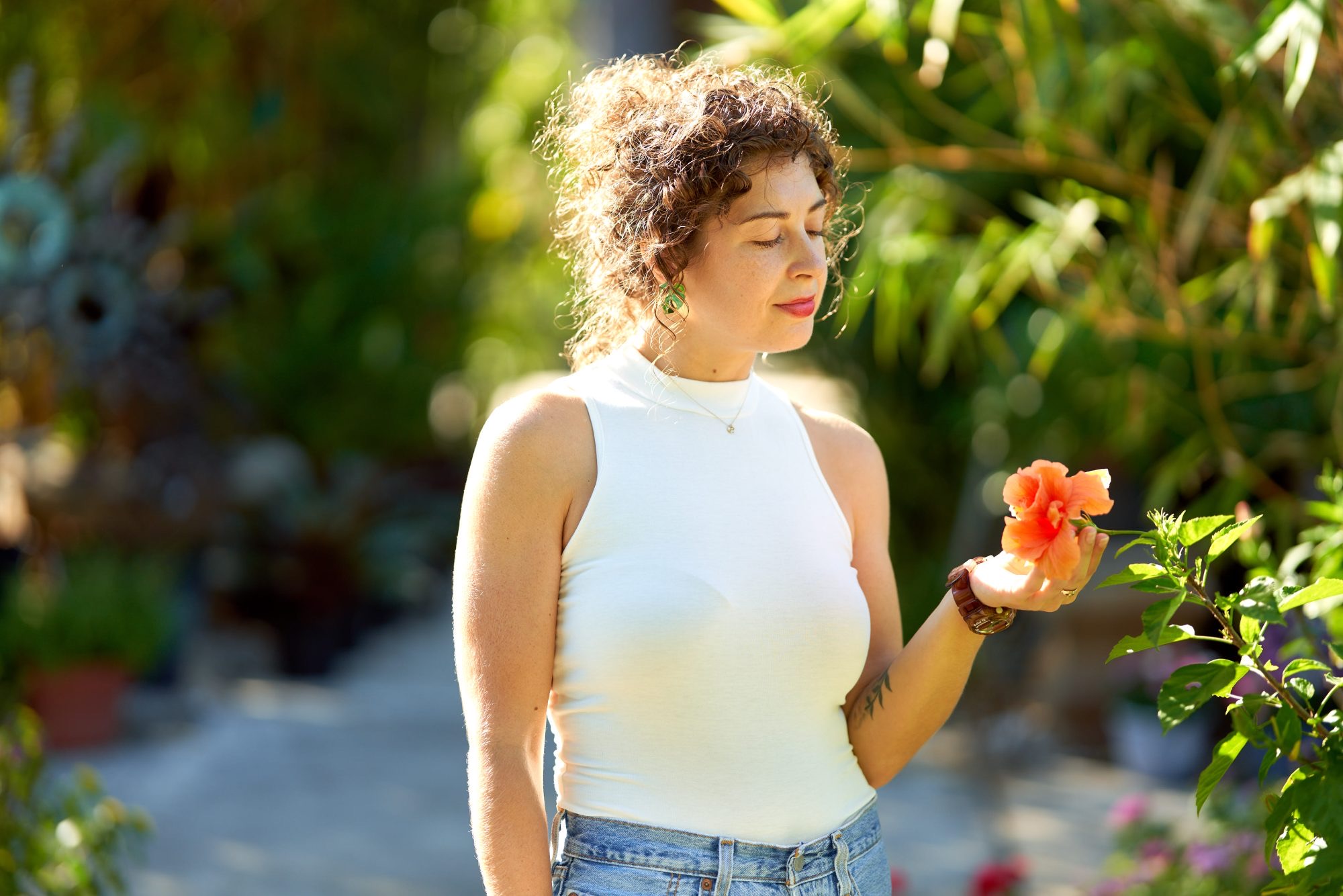 Caitlin holding an orange flower in a sunlit garden